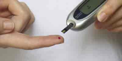Eine Diabetikerin hat einen Blutstropfen auf der Fingerkuppe und testet den Zuckergehalt mit einem Testgerät